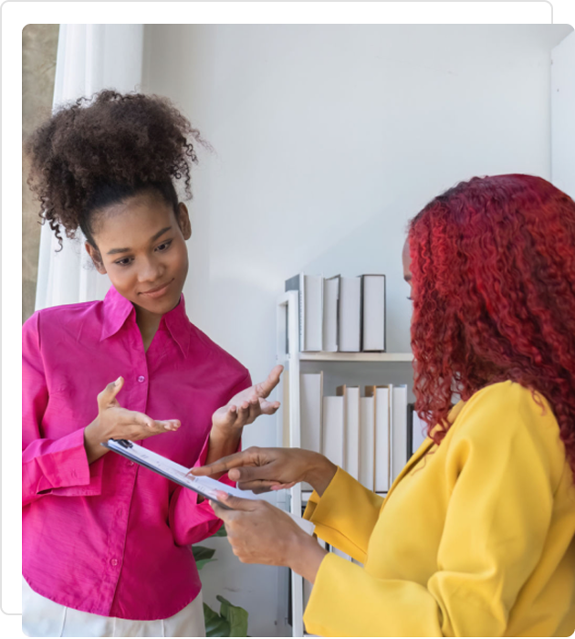 Two women engaged in a discussion, one explaining something with gestures.